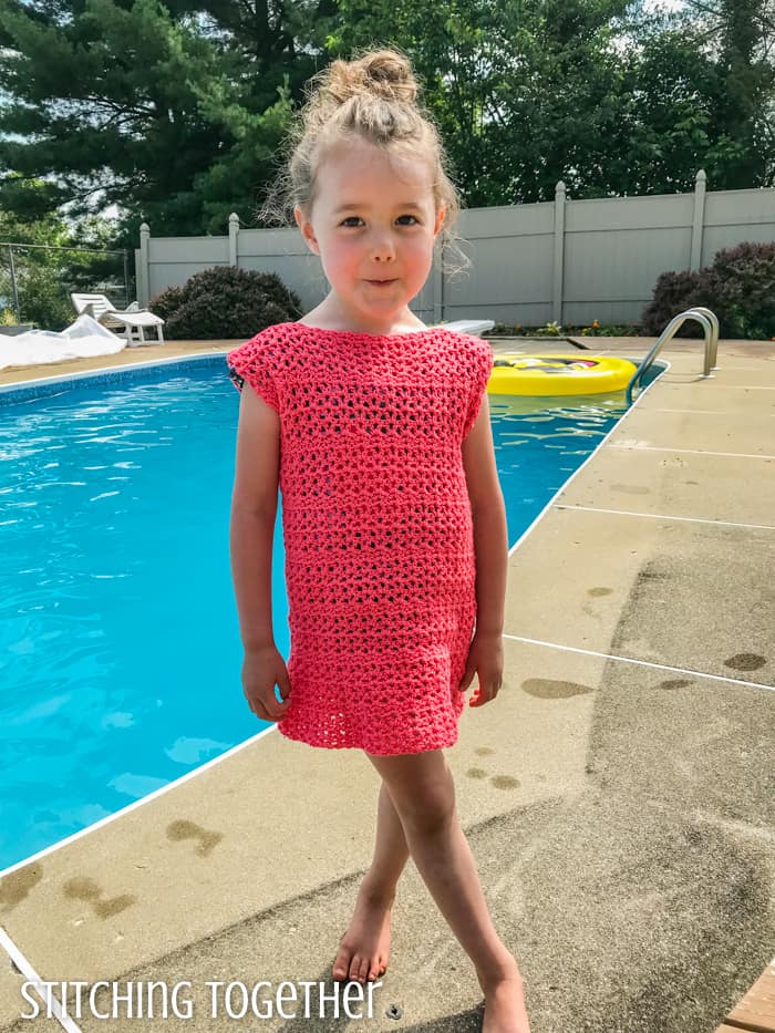 child wearing a pink crochet summer dress while standing by a pool