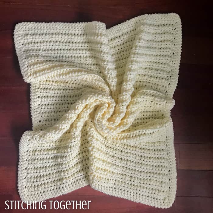 yellow crochet baby blanket on the ground