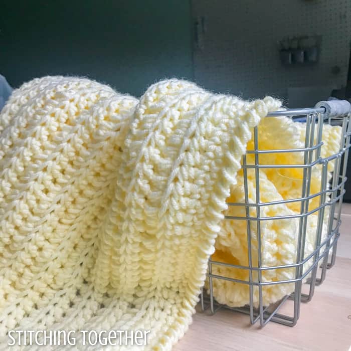 basket with a chunky crochet baby blanket spilling out of it