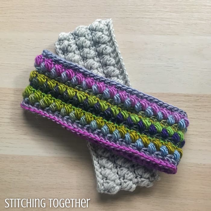 a colorful crochet ear warmer on top of a neutral crochet ear warmer