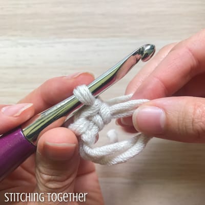 white yarn and purple crochet hook