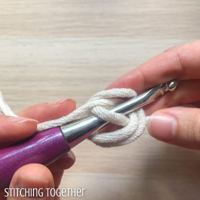 white yarn and purple crochet hook