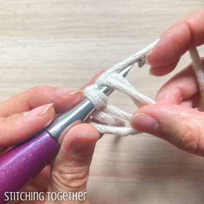 white yarn and purple crochet hook