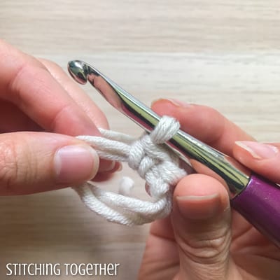 white yarn and purple crochet hook