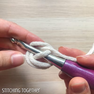 white yarn and purple crochet hook