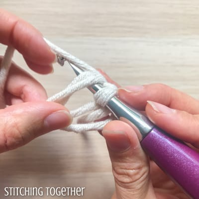 white yarn and purple crochet hook