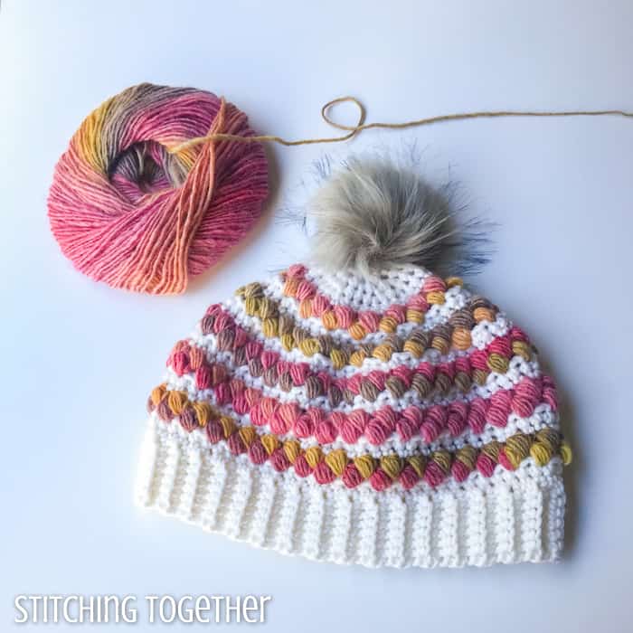 crochet hat for a women with colorful puff stitches and a ball of yarn sitting near