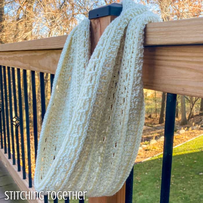 cream crochet infinity scarf hanging on a post