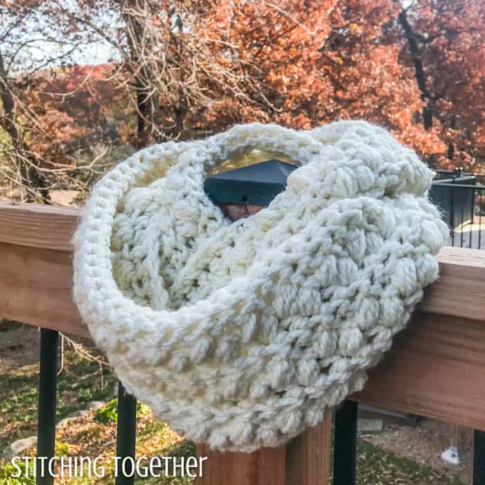 chunky crochet scarf wrapped on the post of a deck