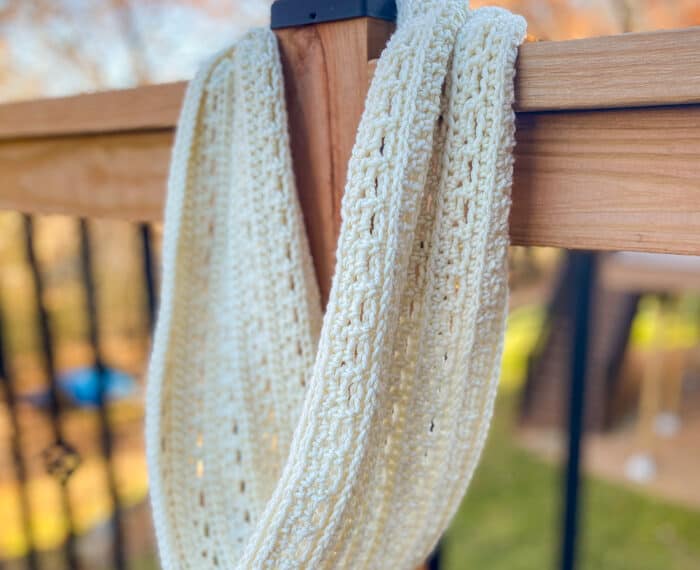 crochet infinity cowl hanging on a deck post
