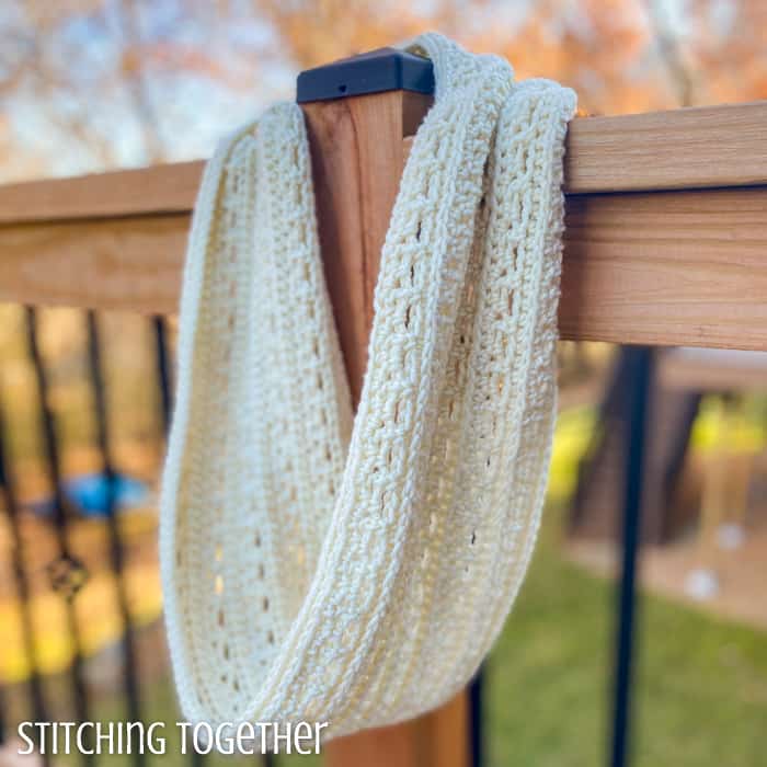 crochet infinity cowl hanging on a deck post