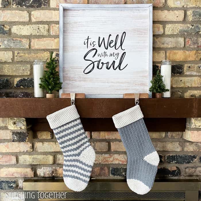 two crochet stockings hanging from a mantle