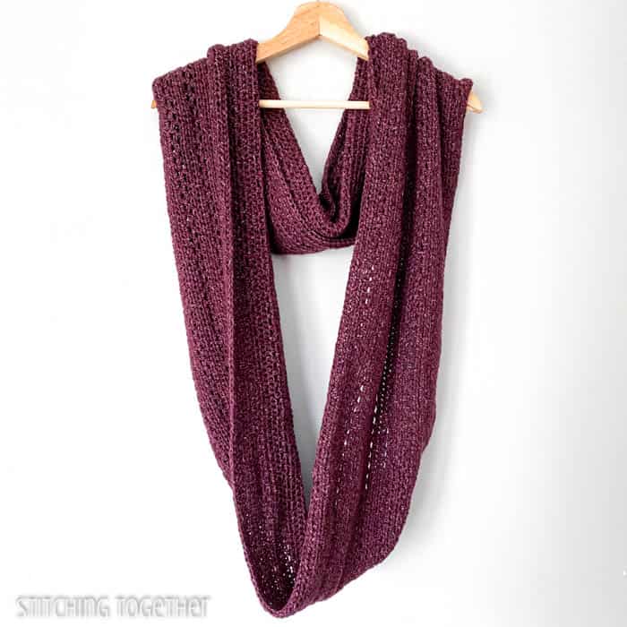 oversized crochet infinity scarf draped on a hanger