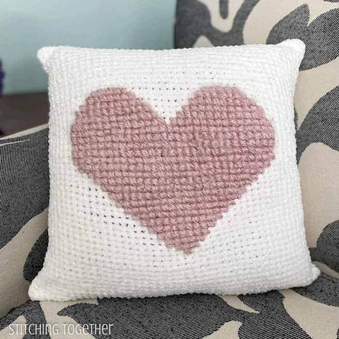 pink heart crochet pillow on white crochet fabric