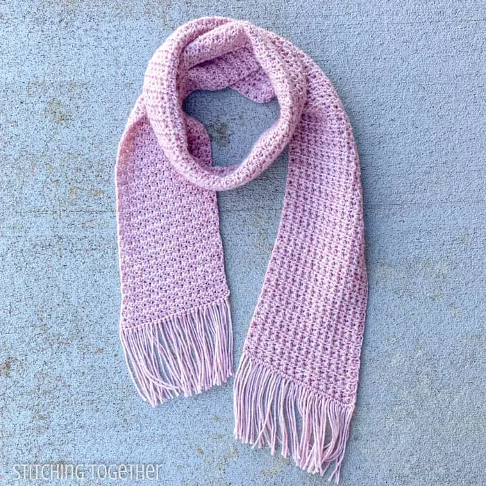 pink crochet fringe scarf displayed on the ground