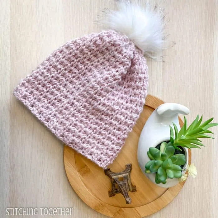 pink crochet beanie with pom pom flat lay
