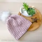 pink crochet beanie hat with pom pom flat lay