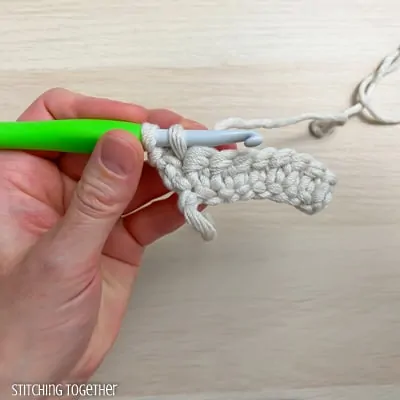 left hand holding yarn and a crochet hook showing the steps of a stitch