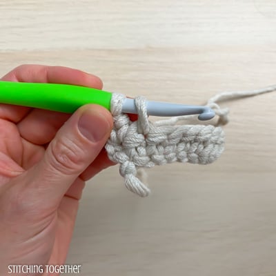 left hand holding yarn and a crochet hook showing the steps of a stitch