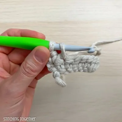 left hand holding yarn and a crochet hook showing the steps of a stitch