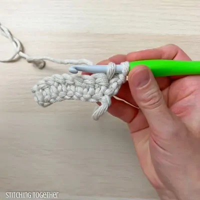 hand holding yarn and a crochet hook showing the steps of a stitch