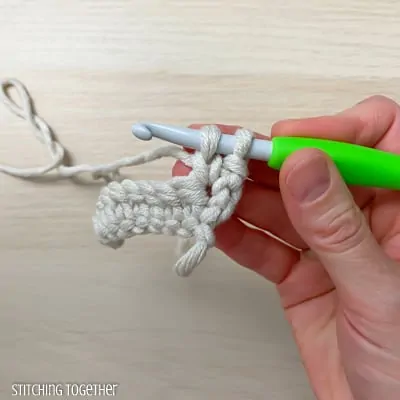 hand holding yarn and a crochet hook showing the steps of a stitch