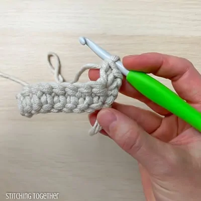 hand holding yarn and a crochet hook showing the steps of a stitch