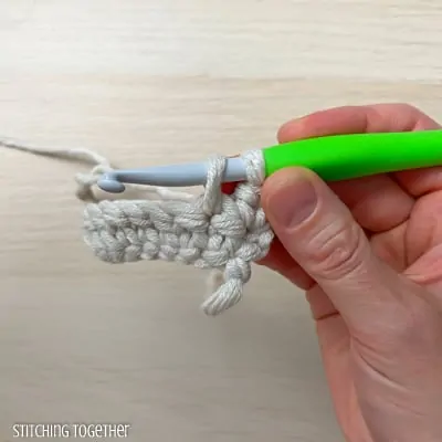 hand holding yarn and a crochet hook showing the steps of a stitch