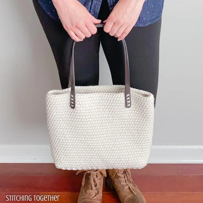 gal holding cream colored crochet bag with faux leather straps