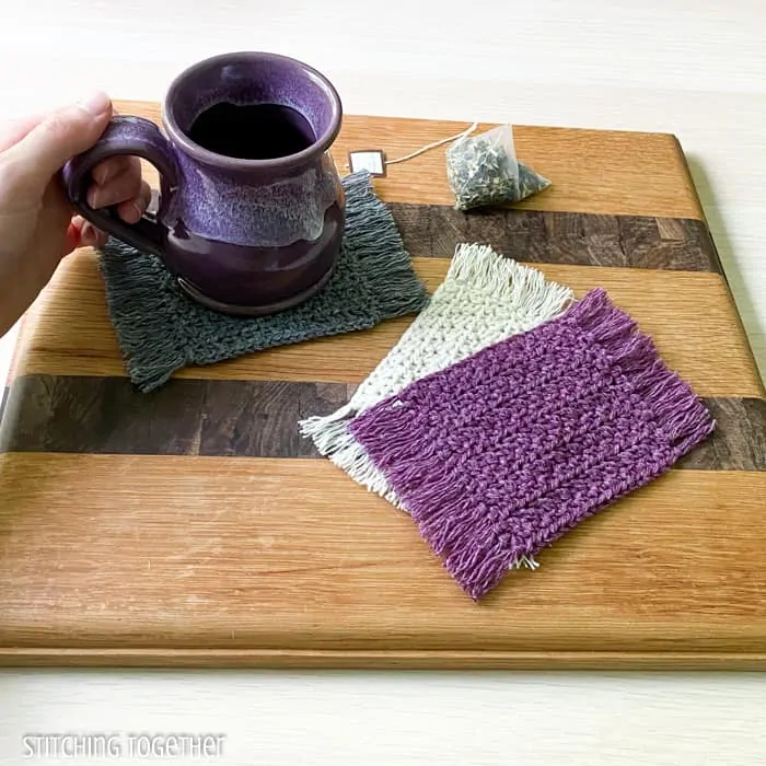 mug sitting on a crochet coaster with 2 other coasters stacked near the mug