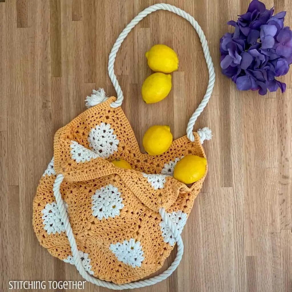 crochet market bag on a counter with lemons and flowers