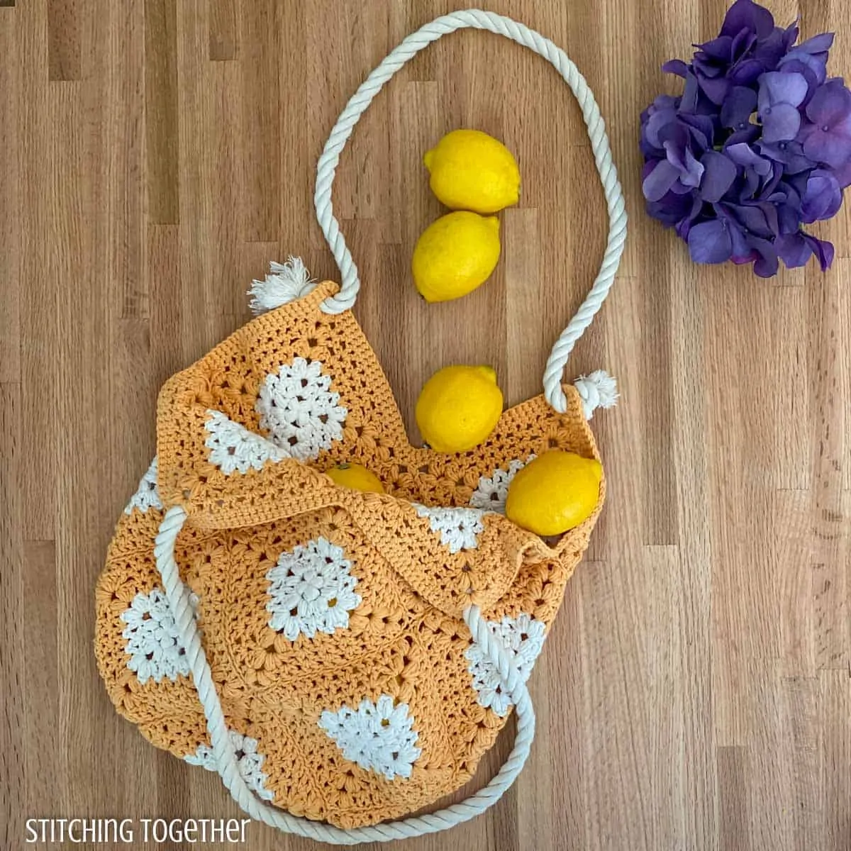 crochet market bag on a counter with lemons and flowers