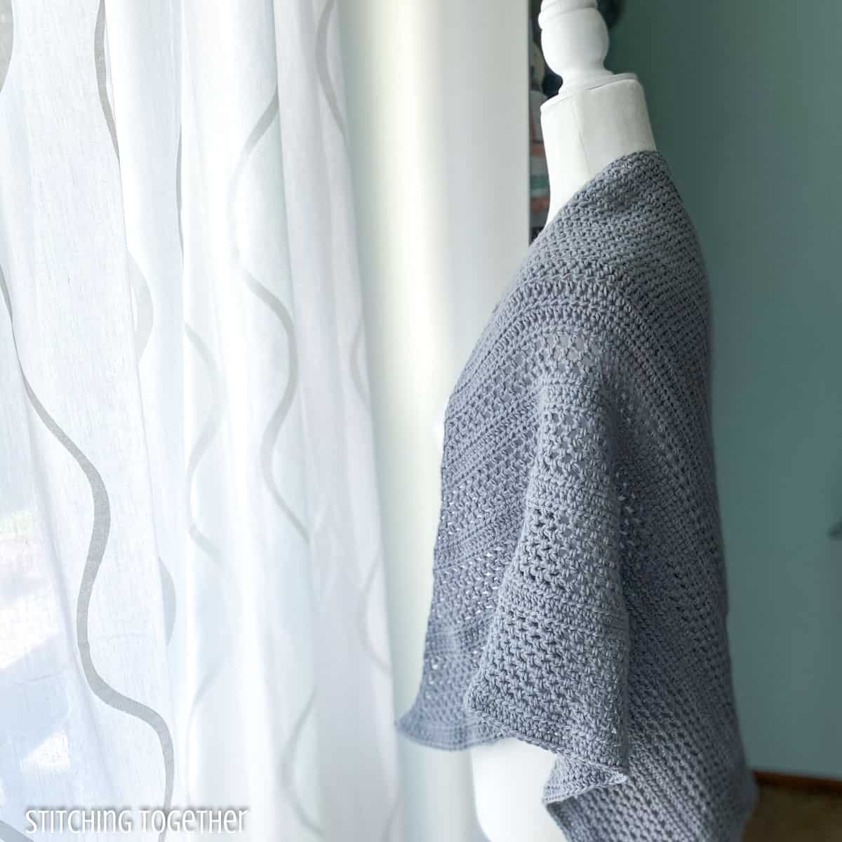 side view of gray crochet shawl on a mannequin