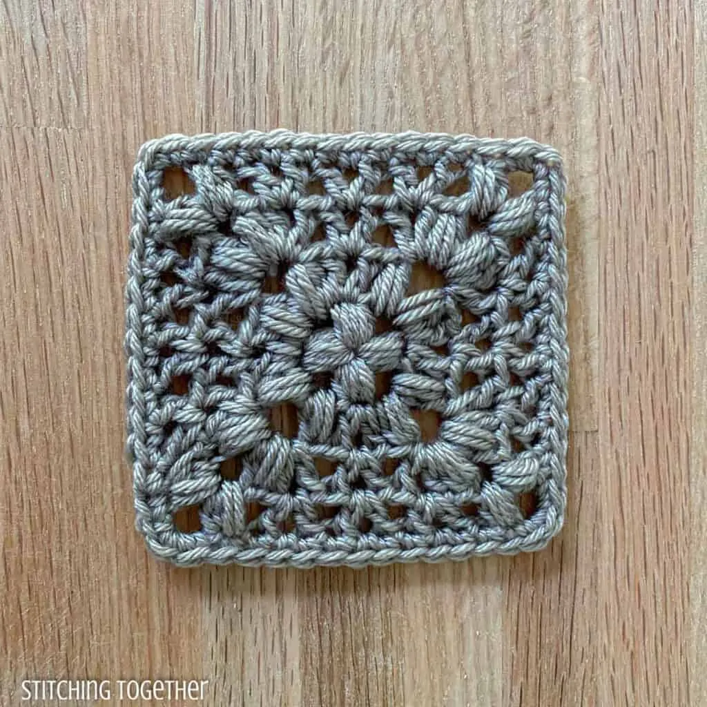 gray crochet granny square with puff stitches and v stitches