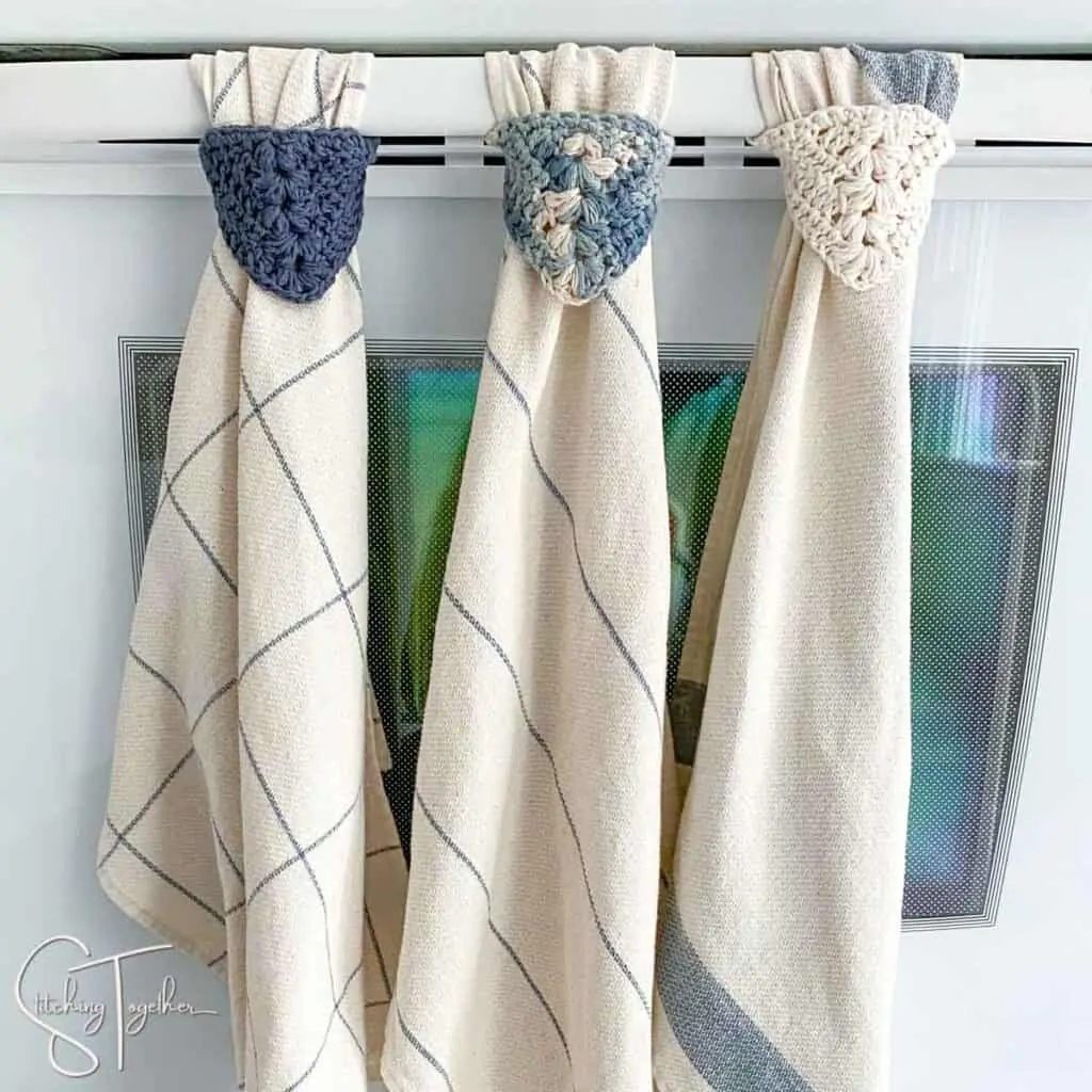 3 crochet towel toppers hanging from oven