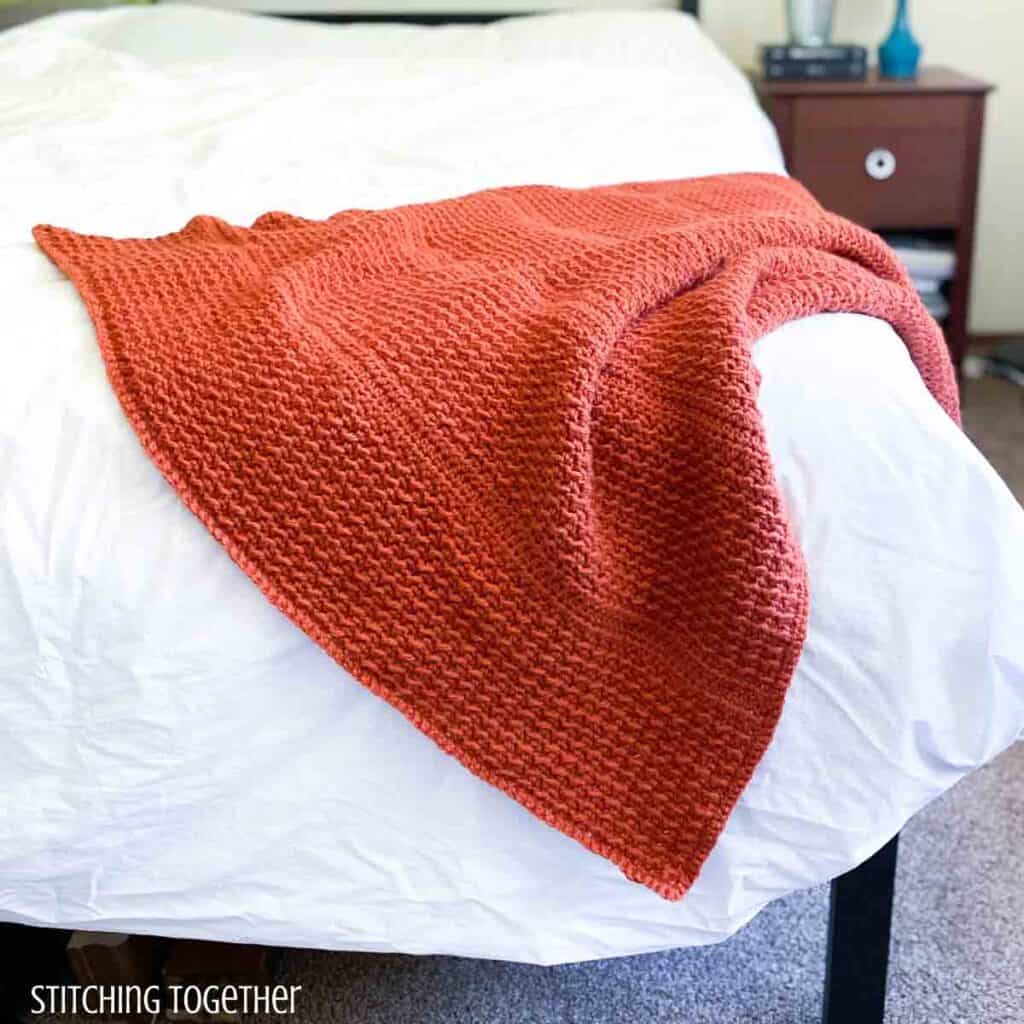 orange crochet throw draped on a bed