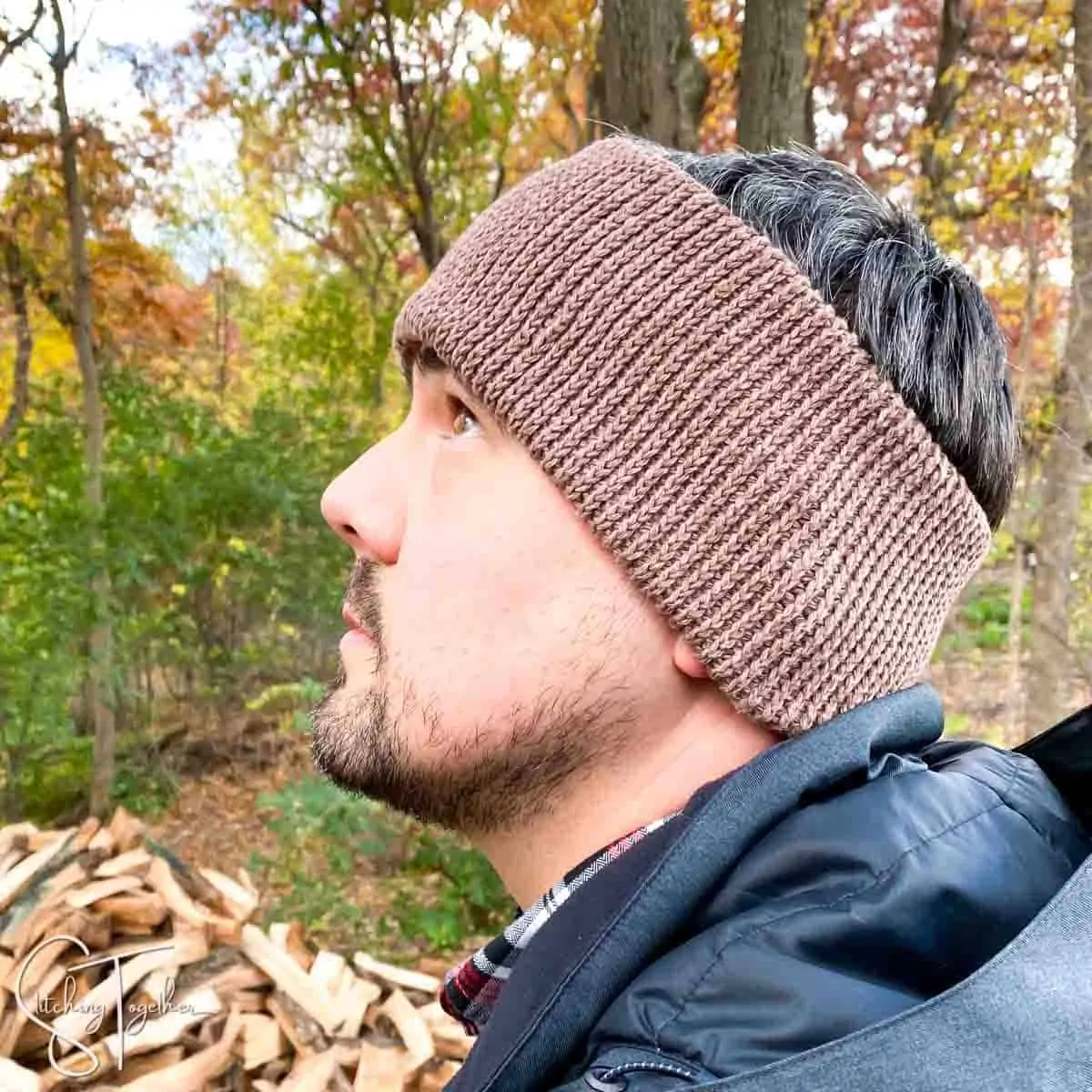 man wearing a brown crochet ear warmer and black jacket