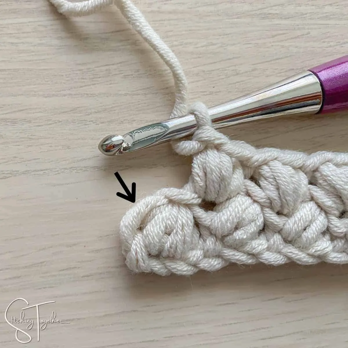arrow showing where to place the last stitch of the row