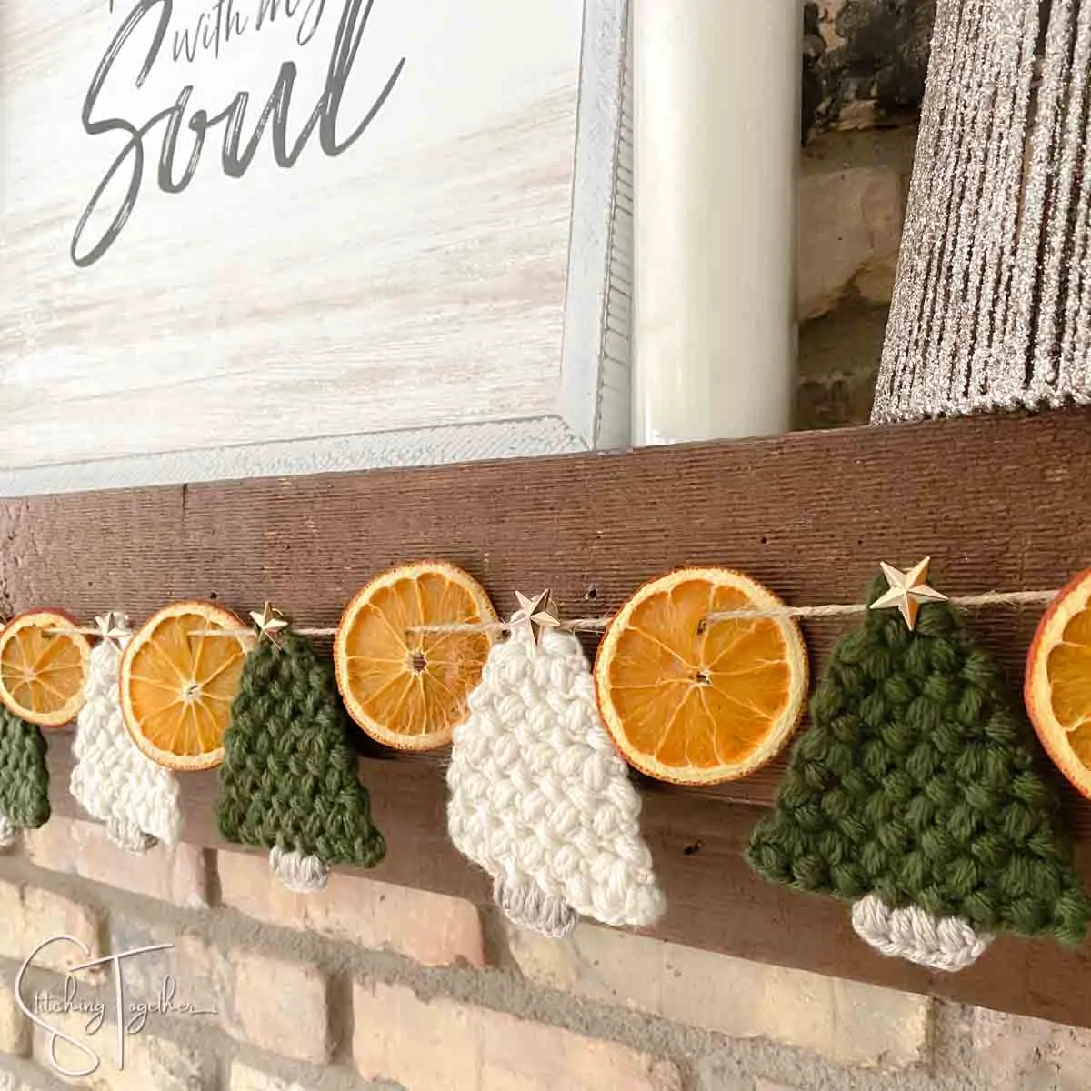 dried orange and crochet christmas tree garland on a fireplace mantle