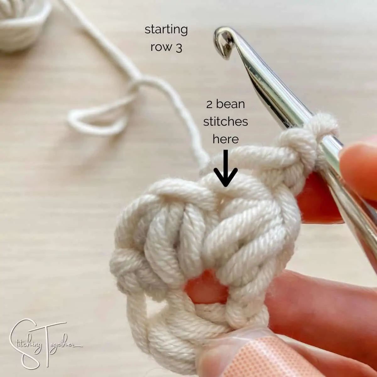 arrow showing where to place the stitches for row 3 (yarn, hook and hand)