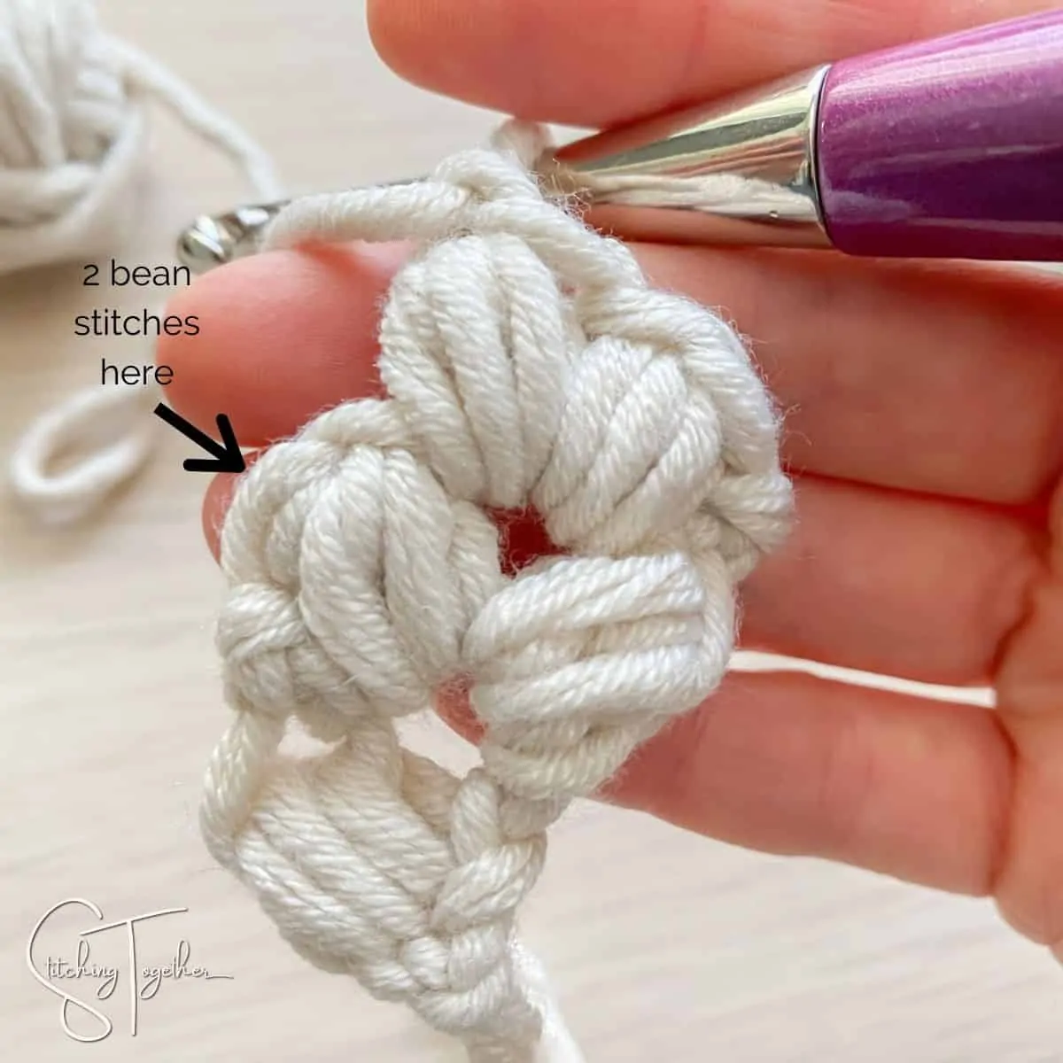 arrow showing where to place the stitches (yarn, hook and hand)