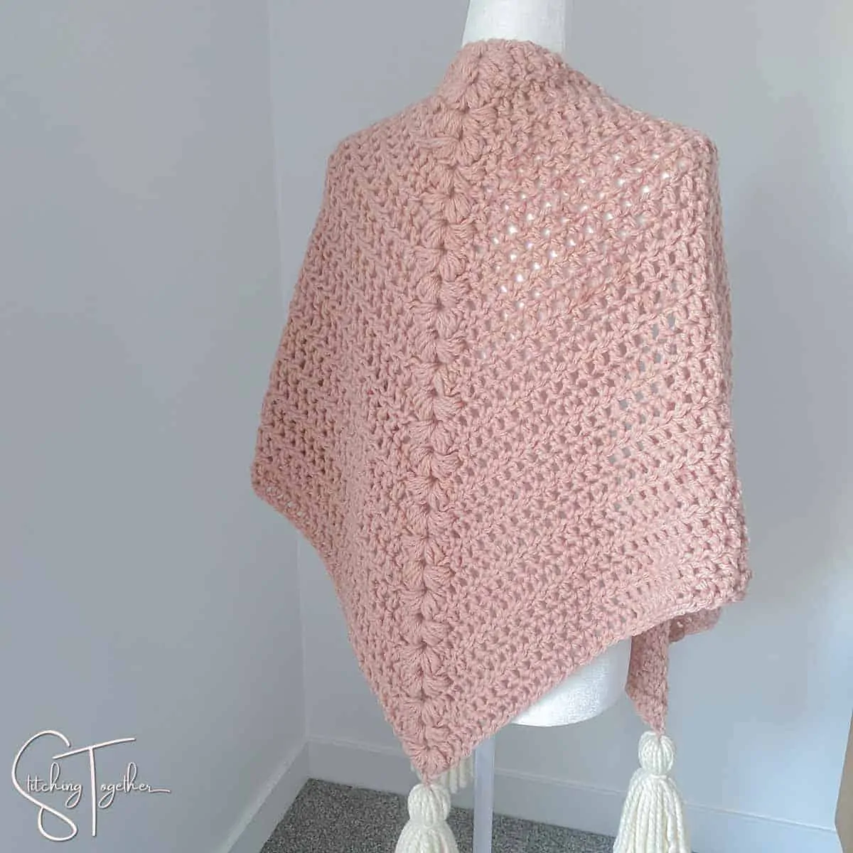 pink chunky triangle shawl with white tassel on a mannequin