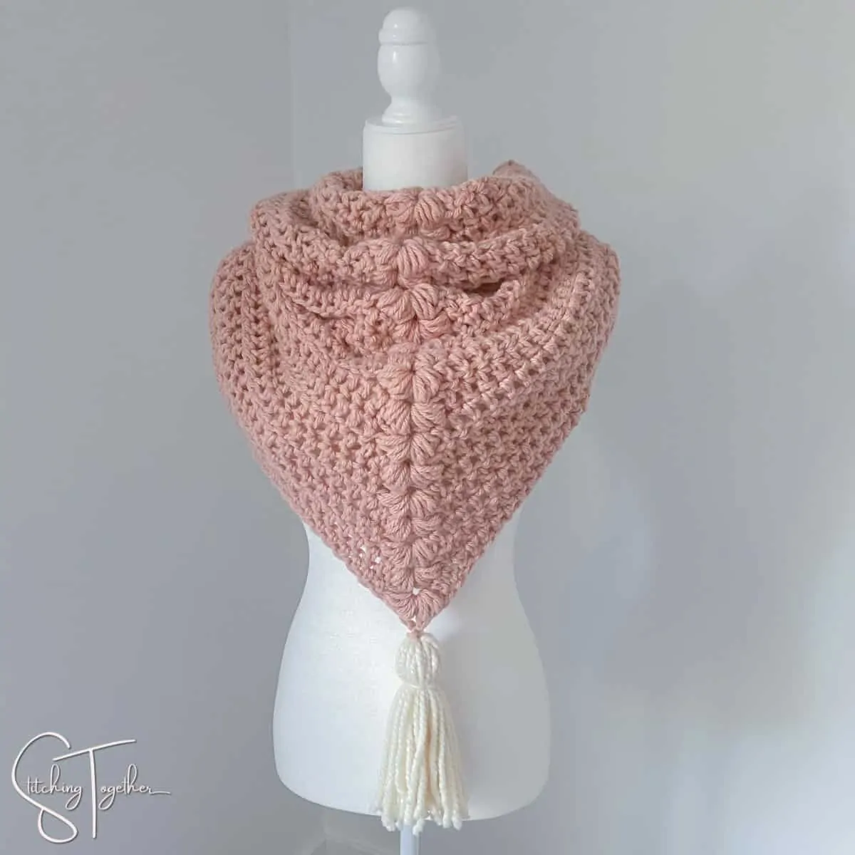 pink chunky triangle scarf with white tassel on a mannequin 