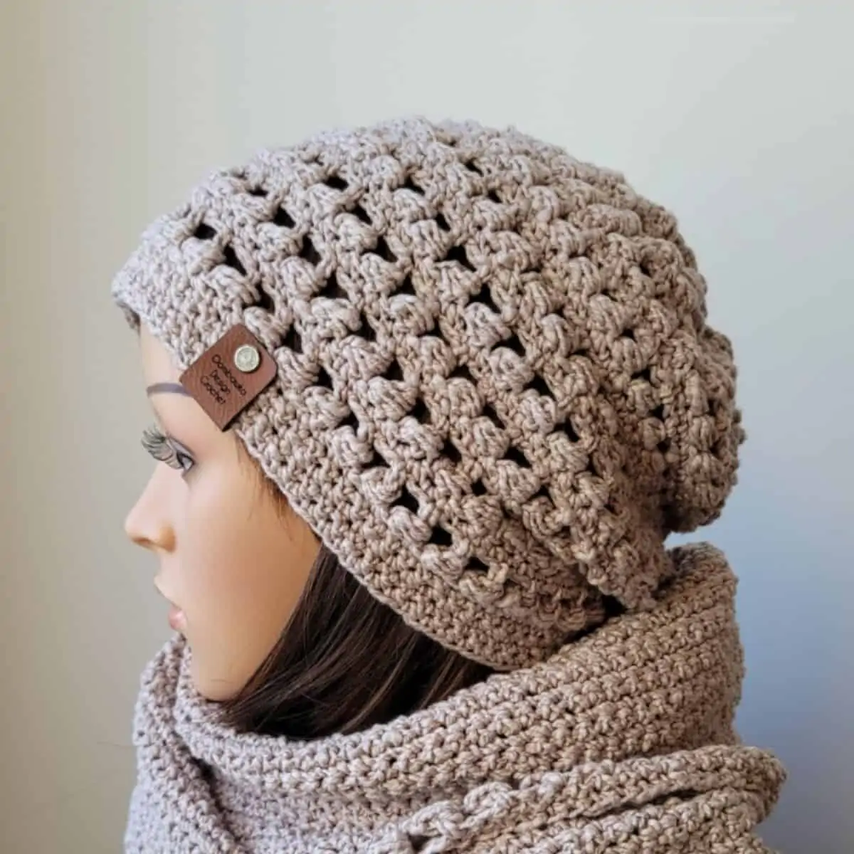 tan colored crochet hat on a mannequin head with a matching scarf