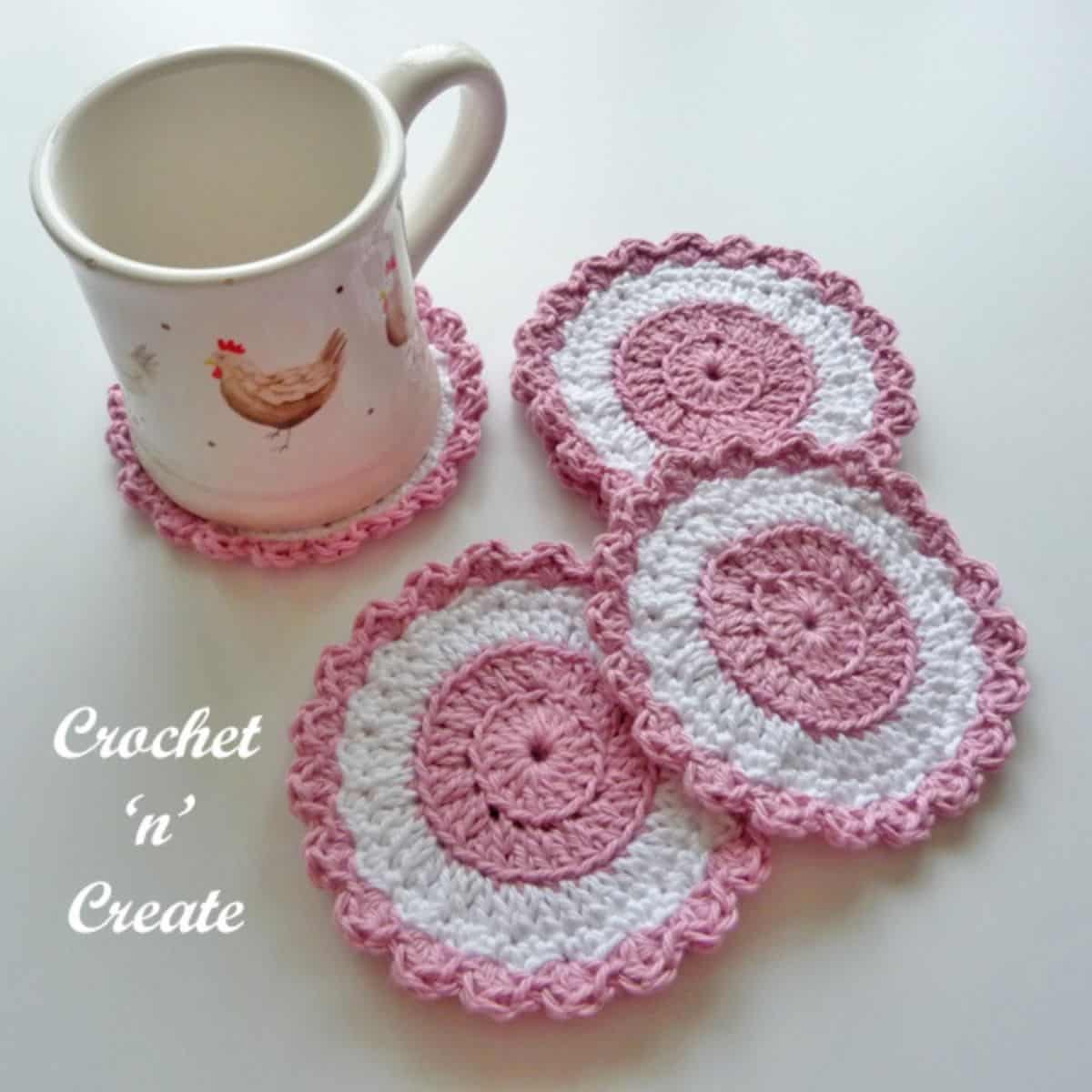 pink and white crochet coasters with a mug sitting on one