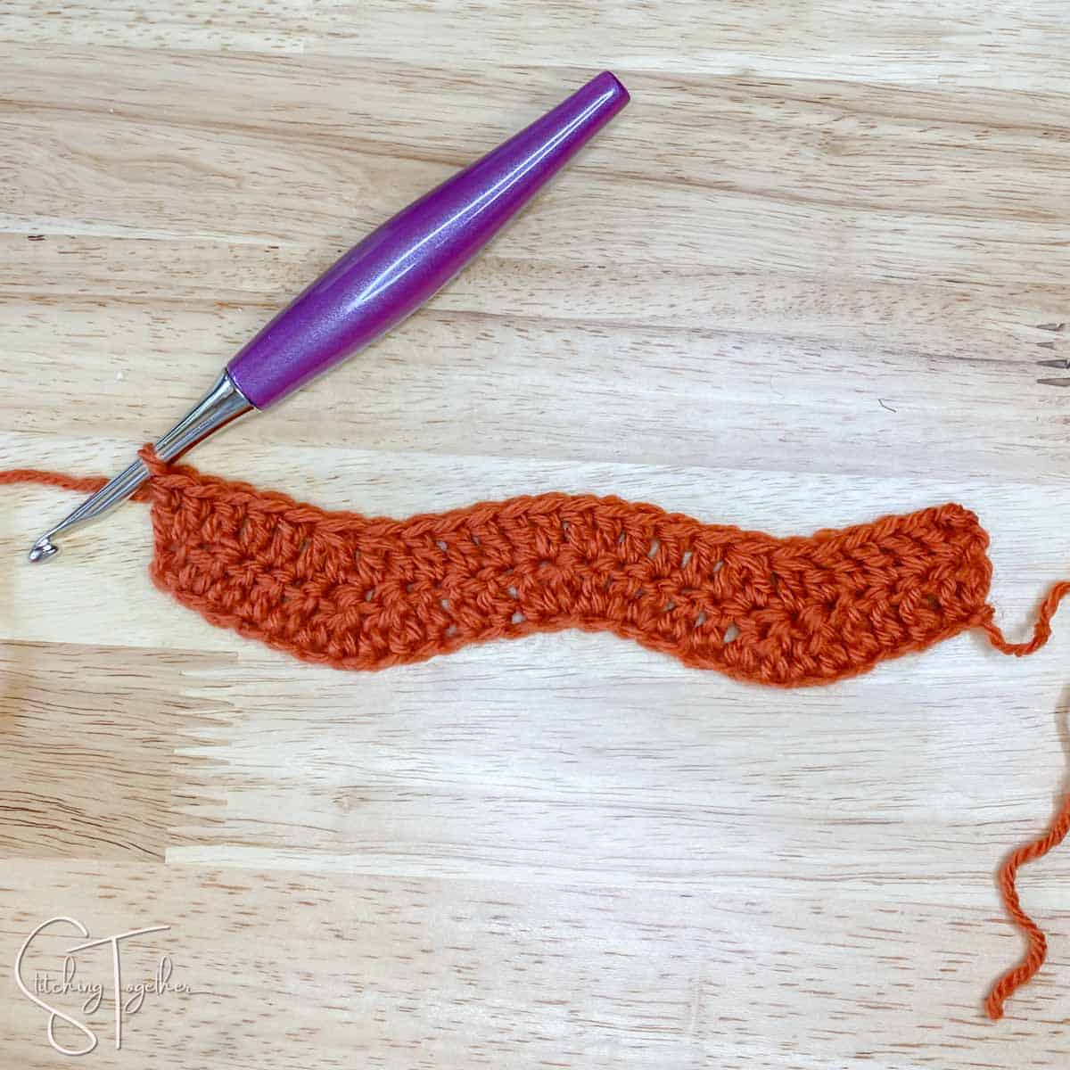 a few rows of competed ripple stitch in orange yarn
