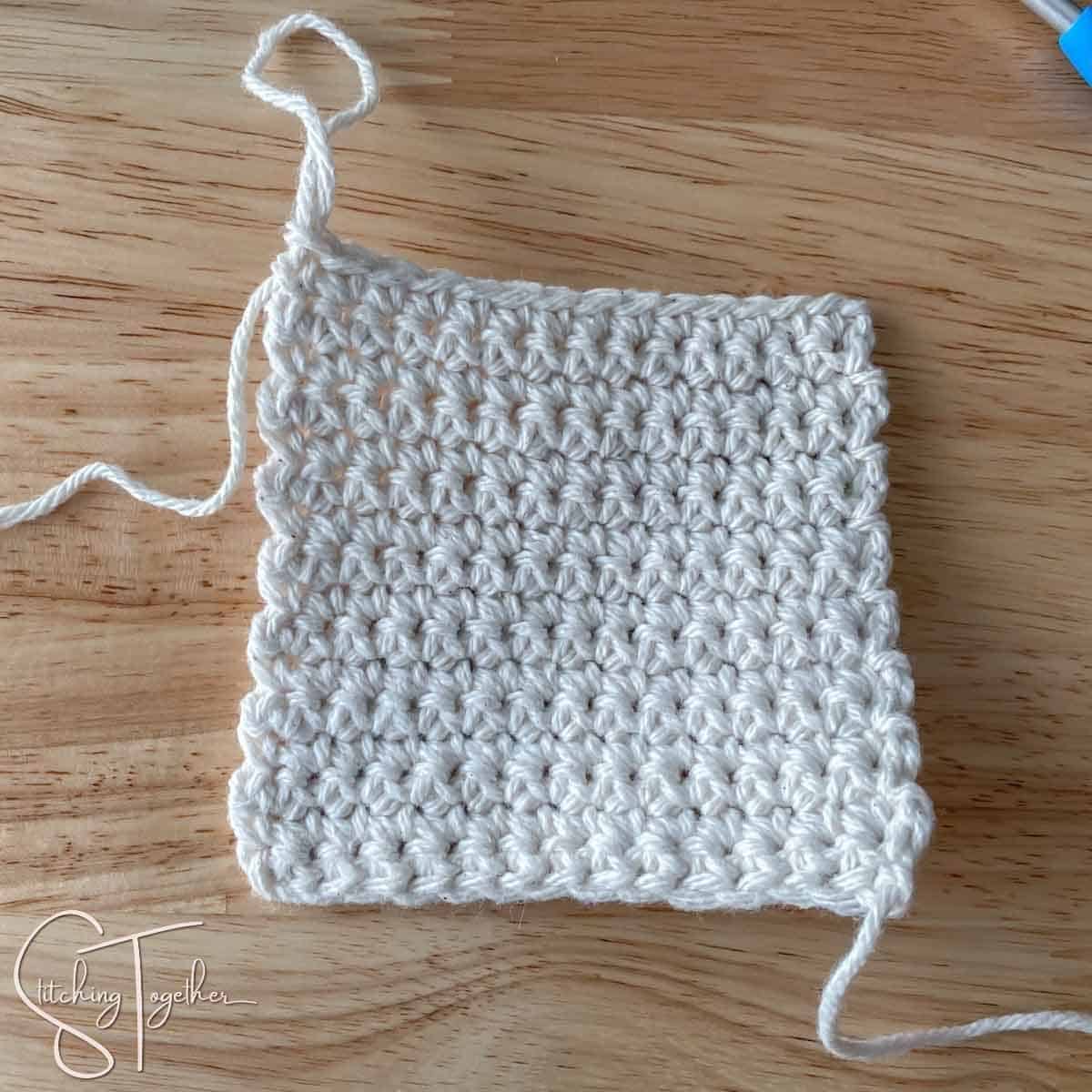 a completed single crochet square with yarn still attached
