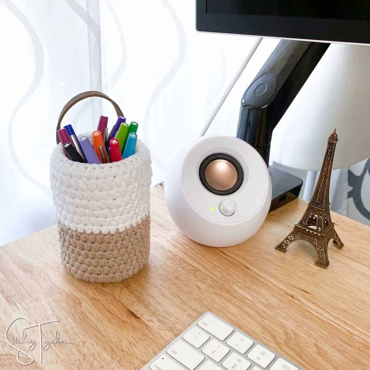 small crochet pen basket filled with colorful pens and sitting on a desk