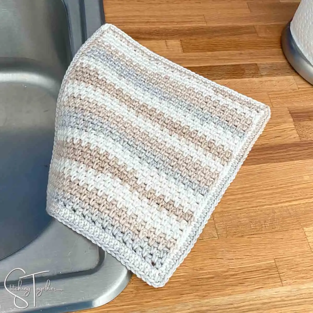 striped crochet moss stitch dishcloth on the side of a sink