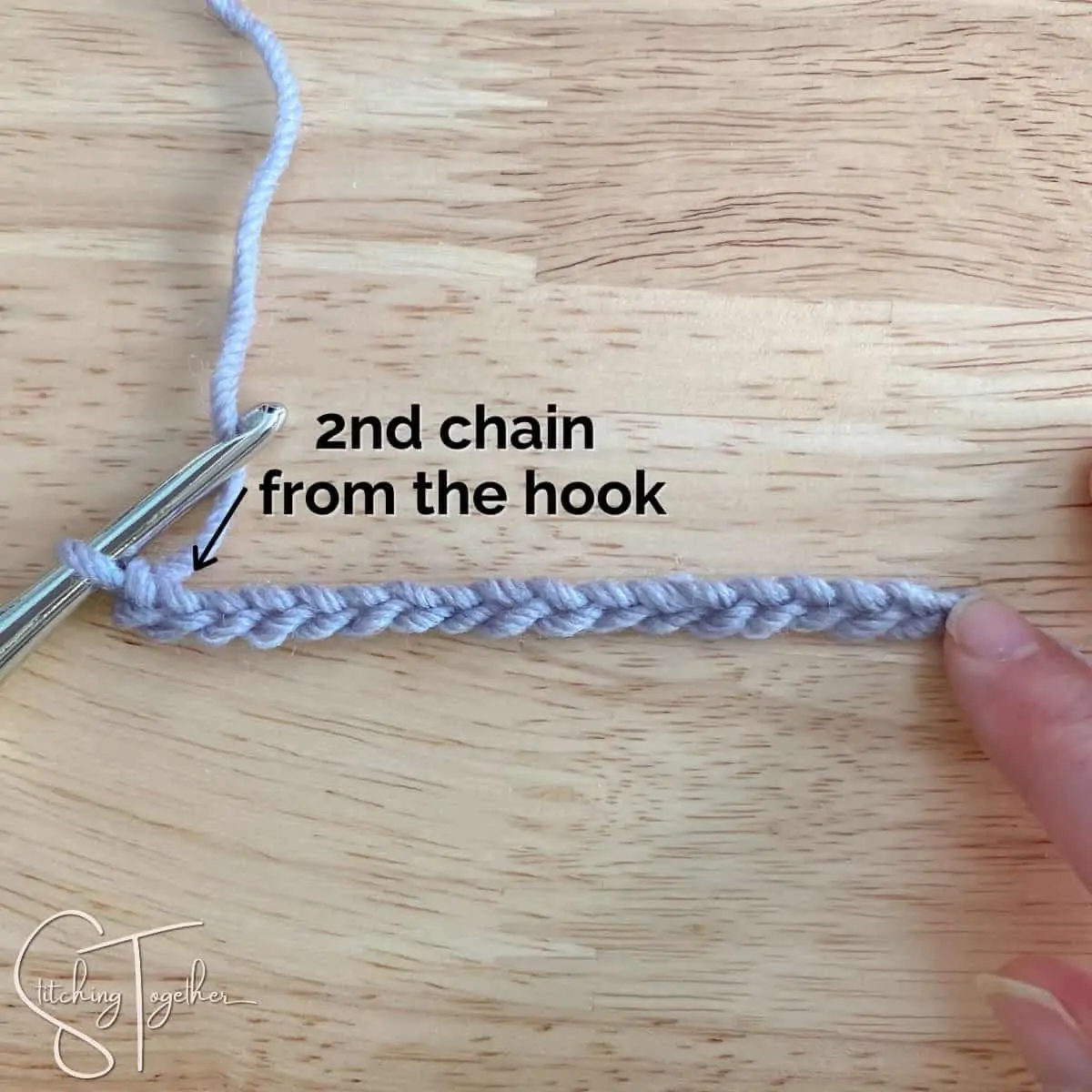 crochet chain with words and an arrow showing the second chain from the hook left